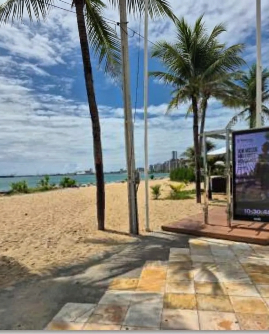 Foto real da campanha: painel digital do Parabank na areia da Beira Mar de Fortaleza, entre coqueiros