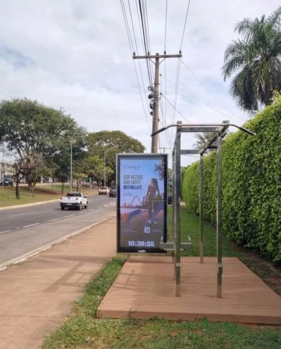 Foto real da campanha: painel digital do Parabank em avenida arborizada do Lago Sul, em Brasília