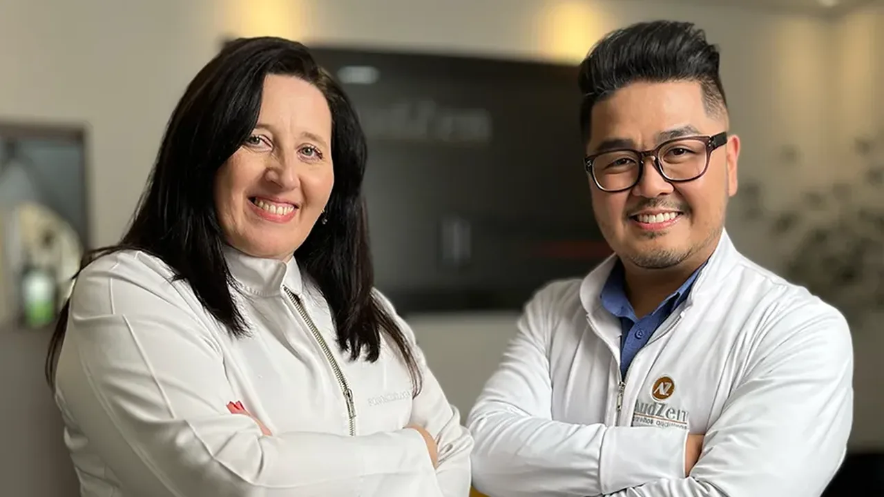 Dupla de fonoaudiólogos da Audzen sorrindo na recepção da clínica